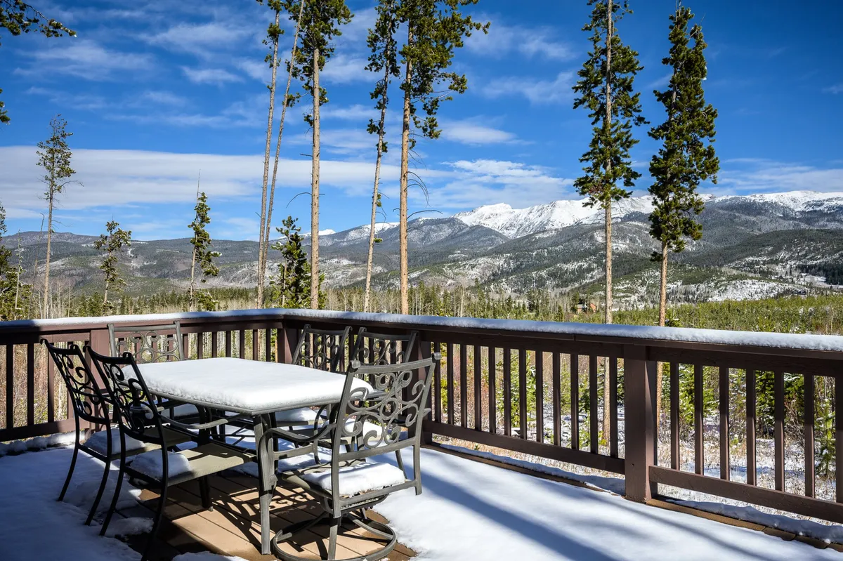 This image captures an outdoor dining table surrounded by trees and set against the backdrop of majestic mountain views. The setting is peaceful and perfect for gatherings, with ample space for group meals and shared moments under the open sky.