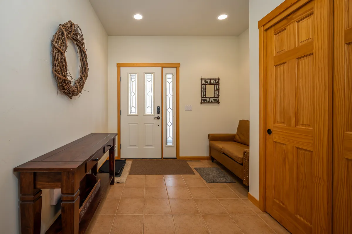 A welcoming entryway that showcases a front door with a decorative wreath, a console table, and a cozy sitting area. The space suggests warmth, secure keyless entry, and an inviting first impression for guests.