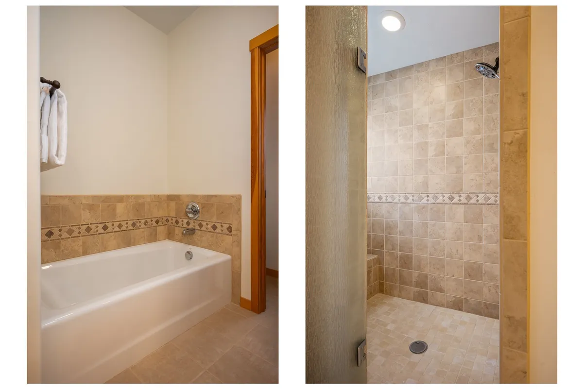 A spacious bathroom featuring a bathtub and shower area with elegant decorative tile trim. The setting exudes spa-like tranquility, ideal for unwinding after a day of mountain adventures.