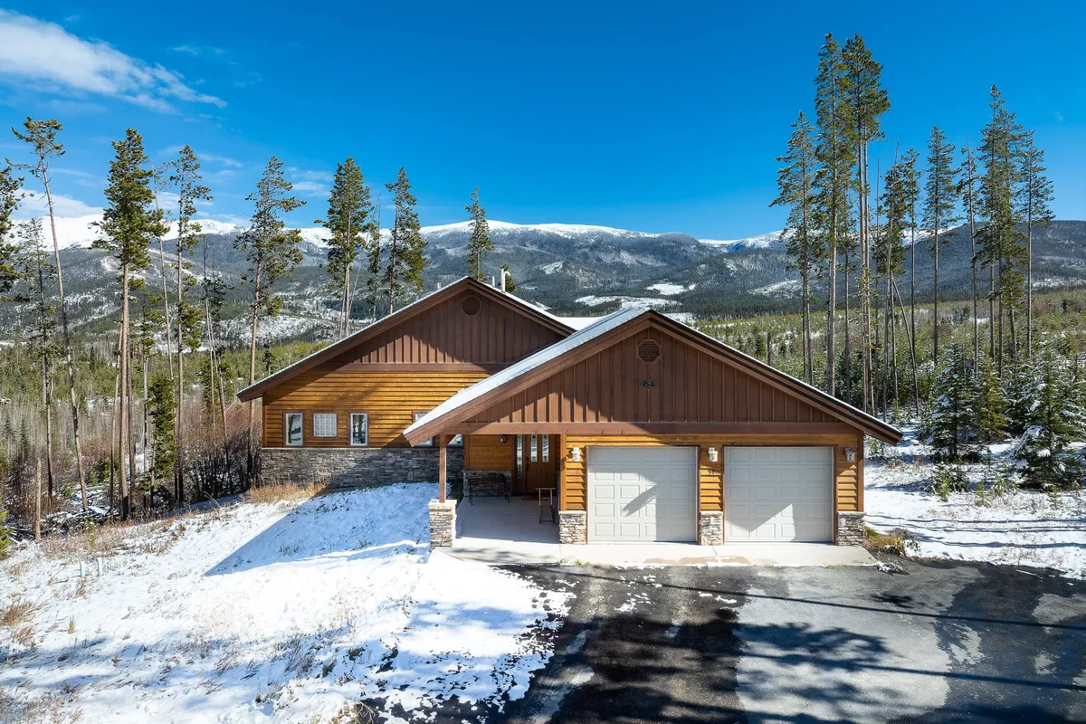 Featuring a classic log cabin structure set amidst a snow-covered landscape with mountains in the background, this image highlights the home's welcoming exterior and its proximity to natural beauty. It conveys both a sense of adventure and a warm retreat.