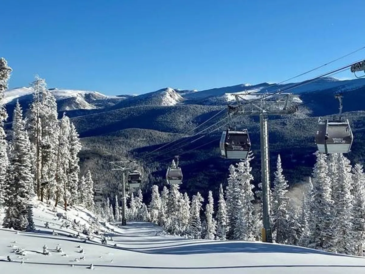An adventurous exterior scene showcasing ski lift gondolas gliding above snow-covered slopes and dense pine trees. The setting sun adds a golden glow to the mountain landscape, and the scene suggests nearby opportunities for skiing, snowboarding, and exploring.
